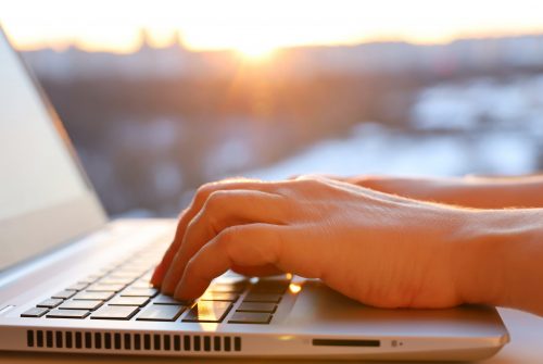 Female,Hands,On,Laptop,Keyboard,Near,The,Window,At,Sunrise.